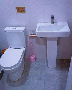 a bathroom with a white toilet and a sink at Wisny Guest House in Kasoa