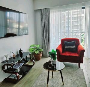 a living room with a red chair and a table at Pinnacle suites in Nairobi
