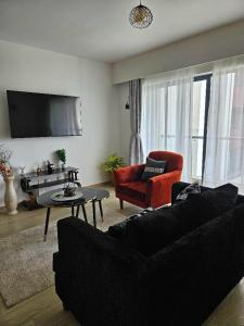 a living room with a black couch and a red chair at Pinnacle suites in Nairobi