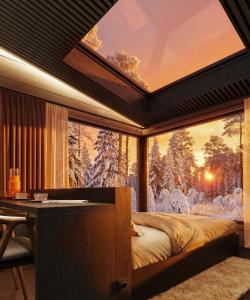 a bedroom with a large window with snow covered trees at ALVA Resort in Rovaniemi