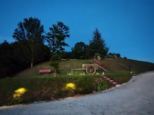 a park with a bench and a wagon on a hill at Sans Chichi Chambres Et Table in Escandolières