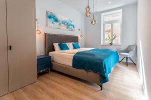 a bedroom with a bed with blue sheets and a chair at Lit Living - Deluxe Apartments - Box Spring - Parking - Neueröffnung - NEW OPENING in Worms