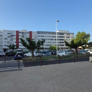 a parking lot with cars parked in front of a building at Studio avec grande terrasse in Carnon-Plage
