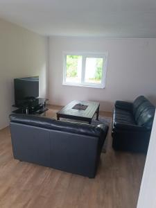 a living room with a black leather couch and a table at Senja Aurora in Senja