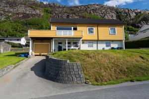 a yellow house on top of a grassy hill at Mountain View Apartment, Free Parking, Hiking Nearby in Ålesund