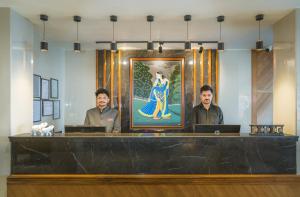 three men standing behind a counter with a picture of a woman at Tripli Hotels M & Resort in McLeod Ganj +104 photos