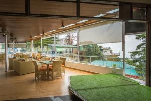 a room with a table and chairs and a large window at Tripli Hotels M & Resort in McLeod Ganj