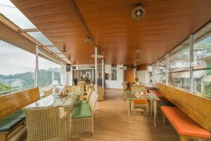 a restaurant with tables and chairs and windows at Tripli Hotels M & Resort in McLeod Ganj