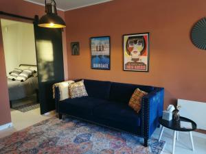 a living room with a blue couch and a bed at Maison Finchette pour 2 - 5 min Saint-Émilion - Terrasse privée - Parking - Arrivée autonome in Sainte-Terre