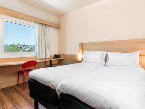 a hotel room with a large bed and a window at ibis Puerto Montt in Puerto Montt