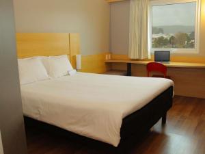 a bedroom with a bed and a desk and a window at ibis Puerto Montt in Puerto Montt +47 photos