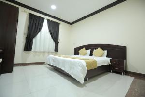 Un dormitorio con una cama grande y una ventana en Alrosa Furnished Apartments, en Buraidah
