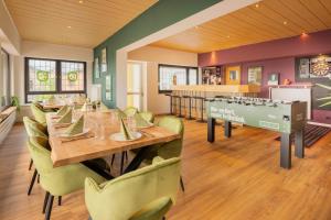 a dining room with a long table and green chairs at The Great View Sauna & more in Harscheid