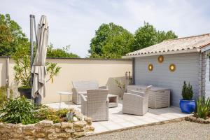a patio with a table and chairs and an umbrella at Gite Romantique de Type Charentais in Le Thou