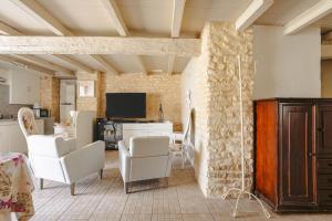 a living room with white chairs and a stone wall at Gite Romantique de Type Charentais in Le Thou