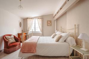 a bedroom with a white bed and a red chair at Gite Romantique de Type Charentais in Le Thou