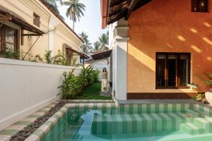a woman standing next to a house with a swimming pool at Forsté Arcangela, Sangolda in Sangolda