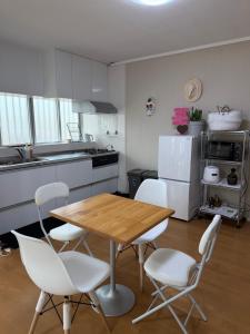 a kitchen with a wooden table and white chairs at MIYARA GARDEN House in Ishigaki Island