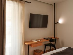 a bedroom with a desk and a television on the wall at Nostos - Luxury Apartment in Agrinio in Agrinio
