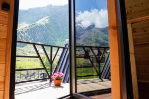 a room with a view of mountains from a balcony at Kokhta Cottage Kazbegi 2 in Kazbegi