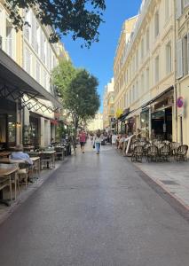 a street with tables and chairs and people walking down the street at One-bedroom apt with balcony on Rue Hoche in Cannes