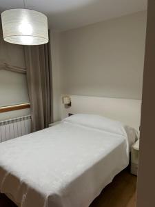 a bedroom with a white bed and a lamp at Casa Savi in Miño
