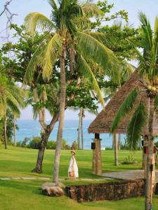 a woman sitting under a palm tree next to a building at Sheraton Sanya Yalong Bay Resort in Sanya