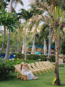a woman sitting on a bench under a palm tree at Sheraton Sanya Yalong Bay Resort in Sanya