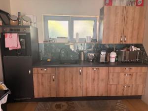 a kitchen with a black refrigerator and wooden cabinets at Privatroom for rent in Bad Fischau +10 photos