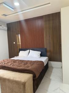 a bedroom with a large bed with a wooden wall at Pristine Residences Premium 2 Bedroom Apartment Ajah Lagos in Lekki