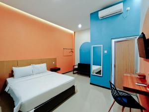 a bedroom with a bed and a blue and orange wall at Tripletree Kenaro Hotel in Blimbing