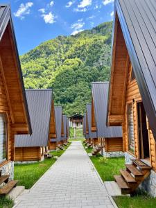 a row of wooden buildings with mountains in the background at Eco Lux Prokletije resort in Gusinje