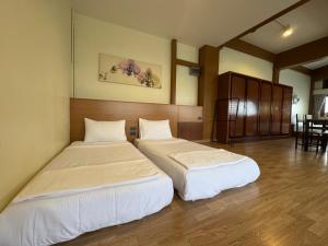 a room with two beds in a room with a table at Sukstay Hotel in Bangkok