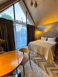 a bedroom with a bed and a table and a large window at ИксаОтель in Shymkent