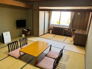 a room with a table and chairs and a television at Shiga Ichii Hotel in Yamanouchi