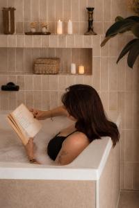 a woman sitting in a bath tub reading a book at Apparts Rennes BnB Duhamel in Rennes +66 photos