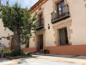 a building with a tree in front of it at El Bulín de Prádena - Calle Real in Prádena del Rincón