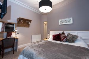 1 dormitorio con cama, escritorio y lámpara en Parkwood Hotel, en Stockton-on-Tees