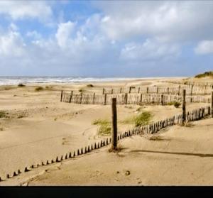 a fence in the sand on a beach at Maison AMARE 200 m de la plage in Berck-sur-Mer