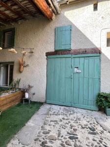 a green garage door with a window on the side of a house at Cozy independent apartment in Mornant