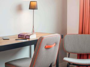 a room with a desk with two chairs and a lamp at Adagio Paris 19ème Cité de la Musique in Paris