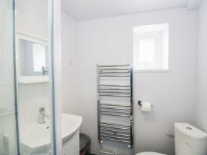 a white bathroom with a toilet and a sink at Oar Cottage in Mablethorpe +15 photos