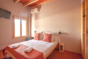 a bedroom with a bed with orange pillows and a window at La Rogeta in Tabarca