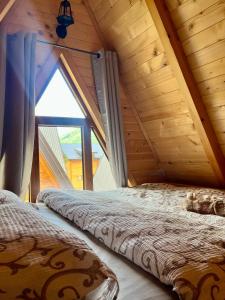 two beds in a attic room with a window at Eco Lux Prokletije resort in Gusinje