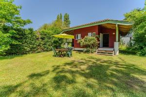 a small red house with a table and umbrella at Le Cabanon Mios in Mios