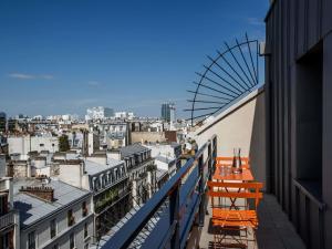 a balcony with orange chairs and a view of a city at Mercure Paris 17 Batignolles in Paris