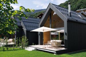 a black house with two chairs and an umbrella at Zalbander Chalets in Silbertal