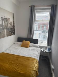 a bedroom with a bed with a yellow blanket and a window at The Cosy Nook in Blackpool