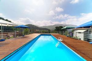 a large swimming pool with a wooden deck next to a house at Gapyeong Ohneulharu Spa Pension Pet friendly in Gapyeong