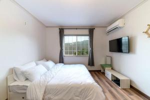 a white bedroom with a bed and a television at Gapyeong Ohneulharu Spa Pension Pet friendly in Gapyeong